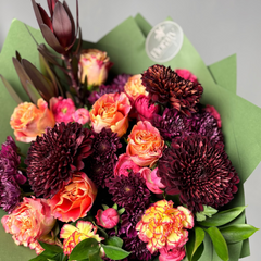 Bouquet of flowers with dark red, orange and pink colors on a light gray background