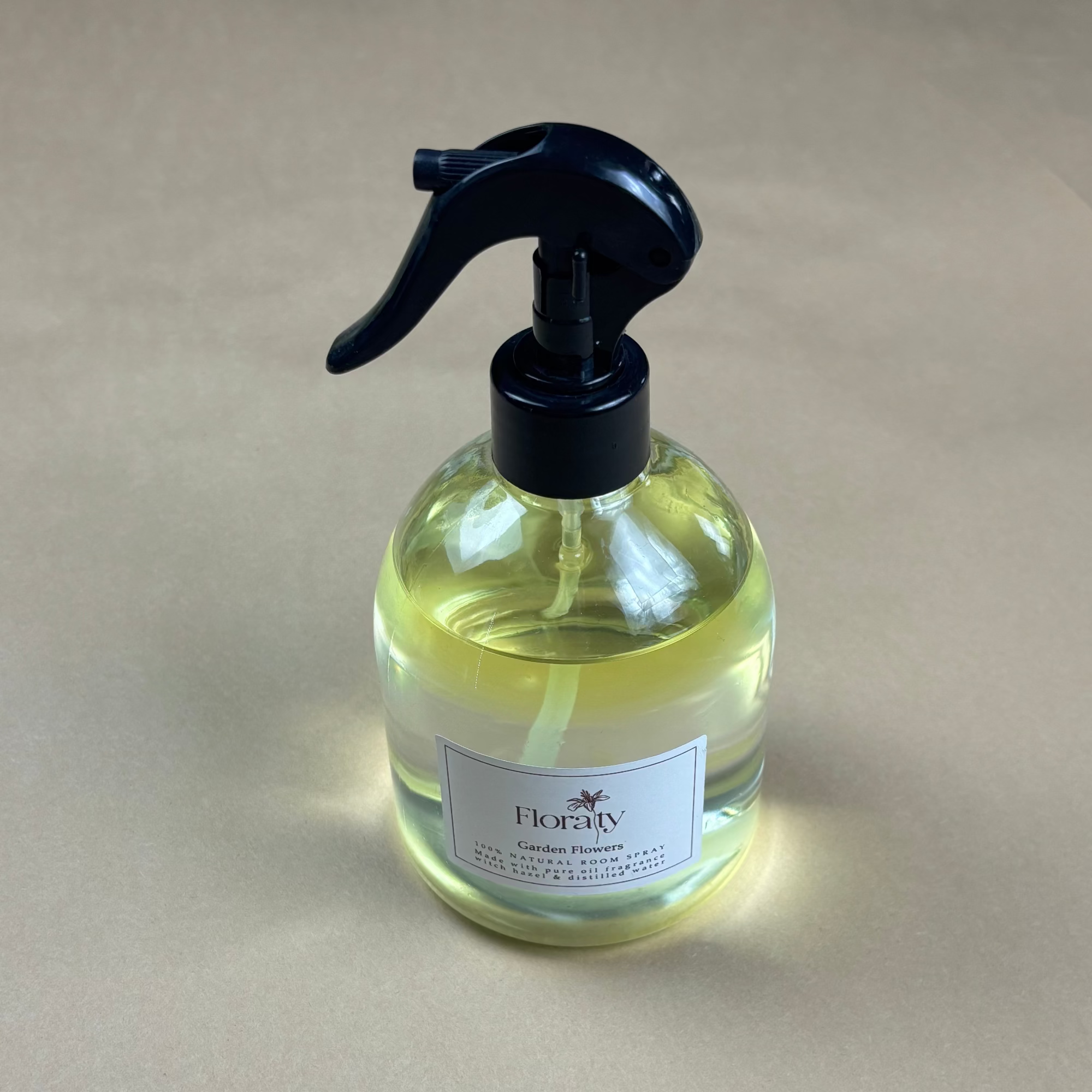 Clear spray bottle with black nozzle on a beige background