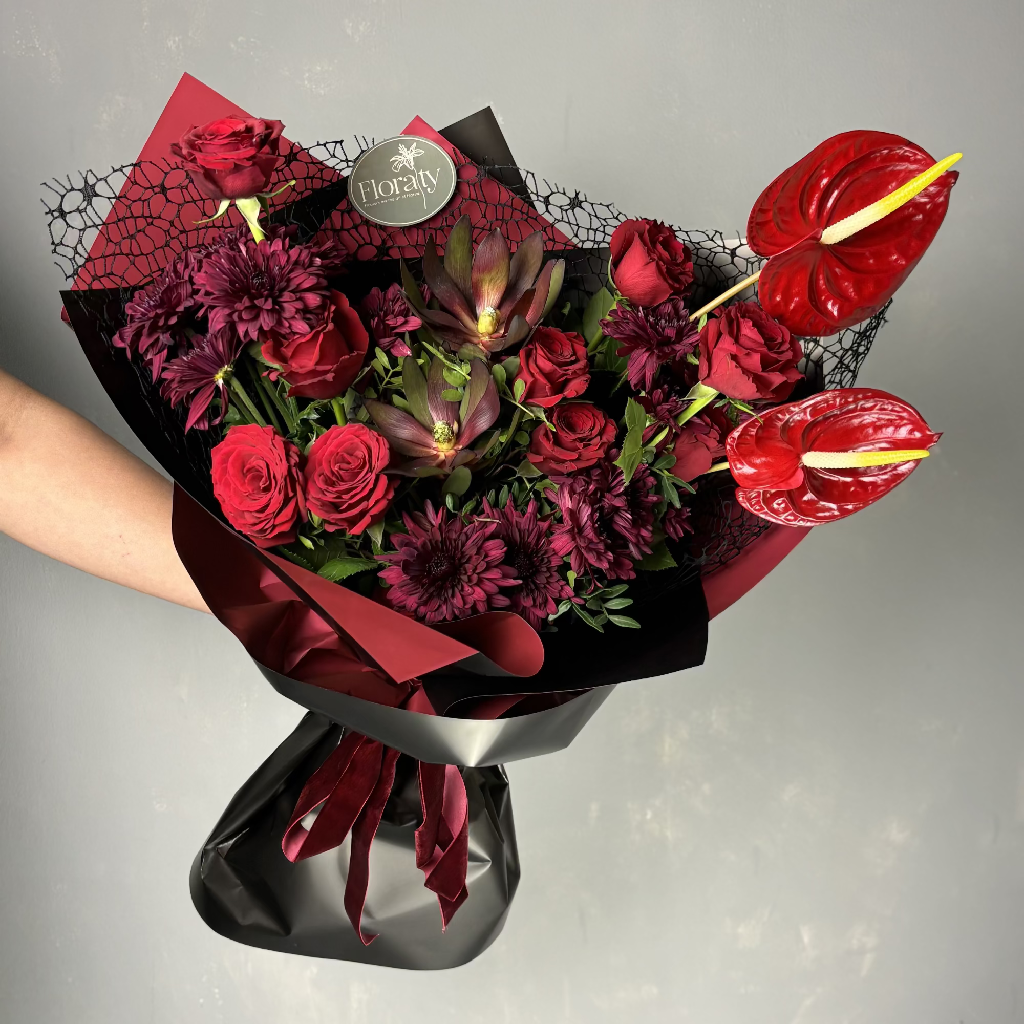 Bouquet of red flowers with anthuriums on a gray background