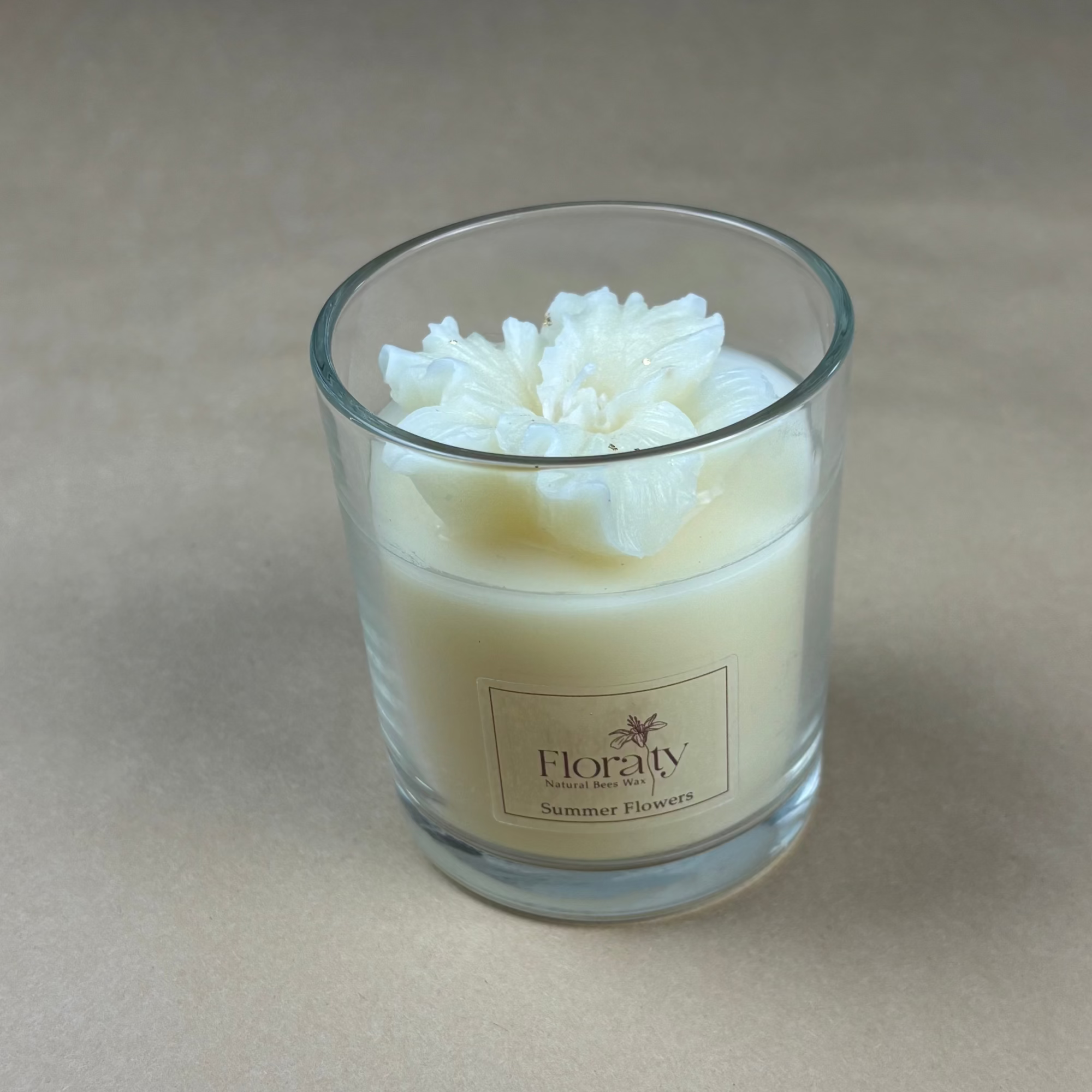 Glass candle with floral design on a beige background