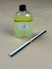 Clear bottle with yellow liquid and black cap on a beige background