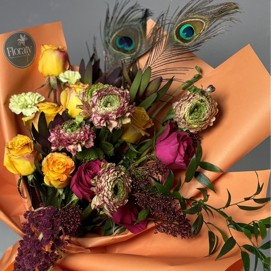 Bouquet of flowers with peacock feathers on orange paper, brand 'Floraty' visible