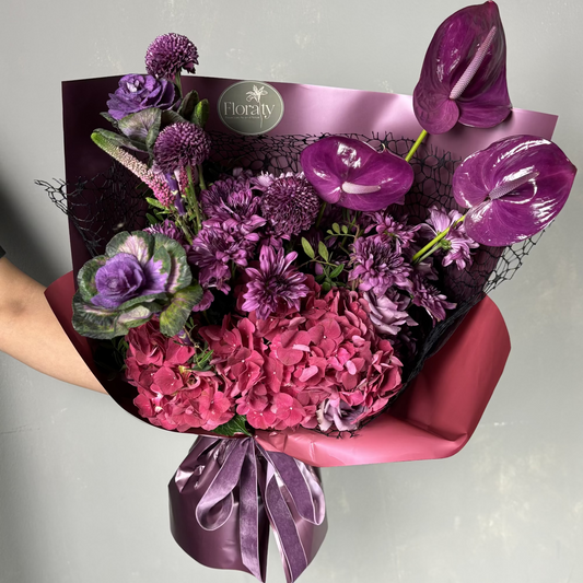 Bouquet of purple and pink flowers with a visible brand label on a light gray background