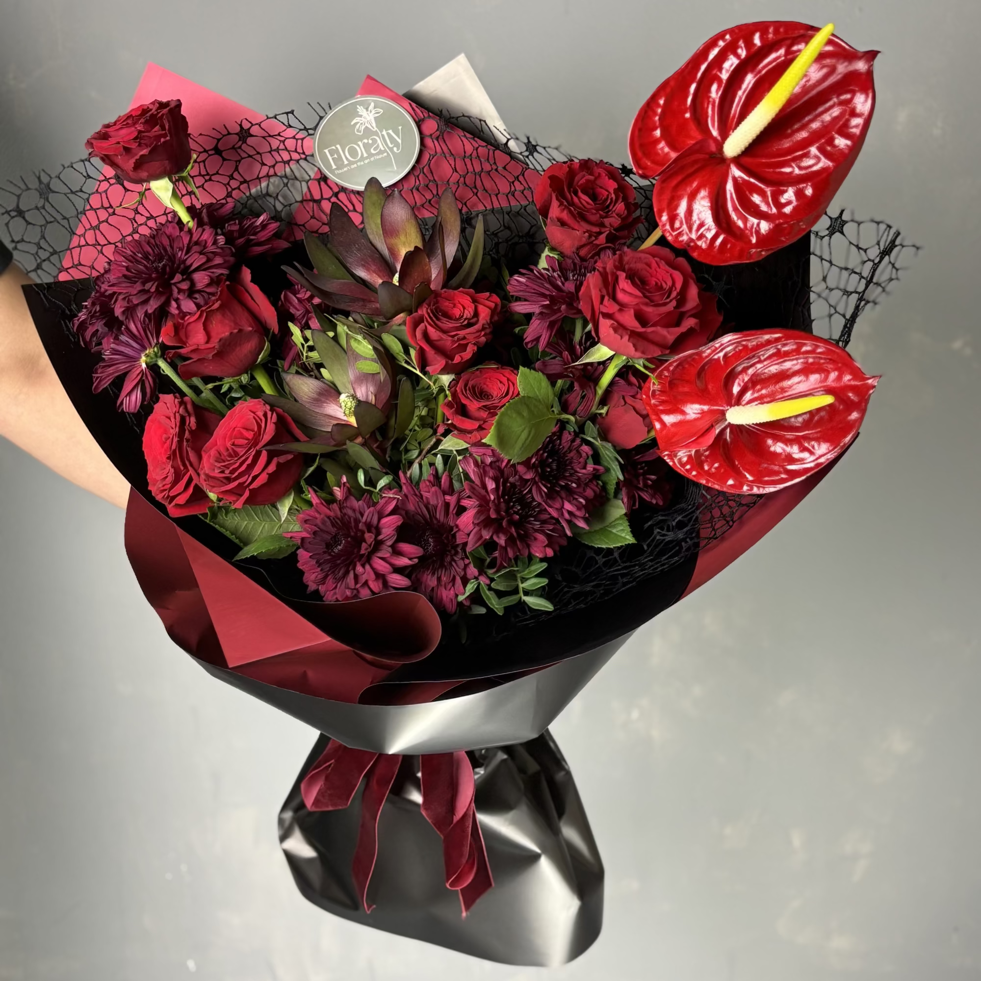 Bouquet of red flowers with a black wrap on a gray background
