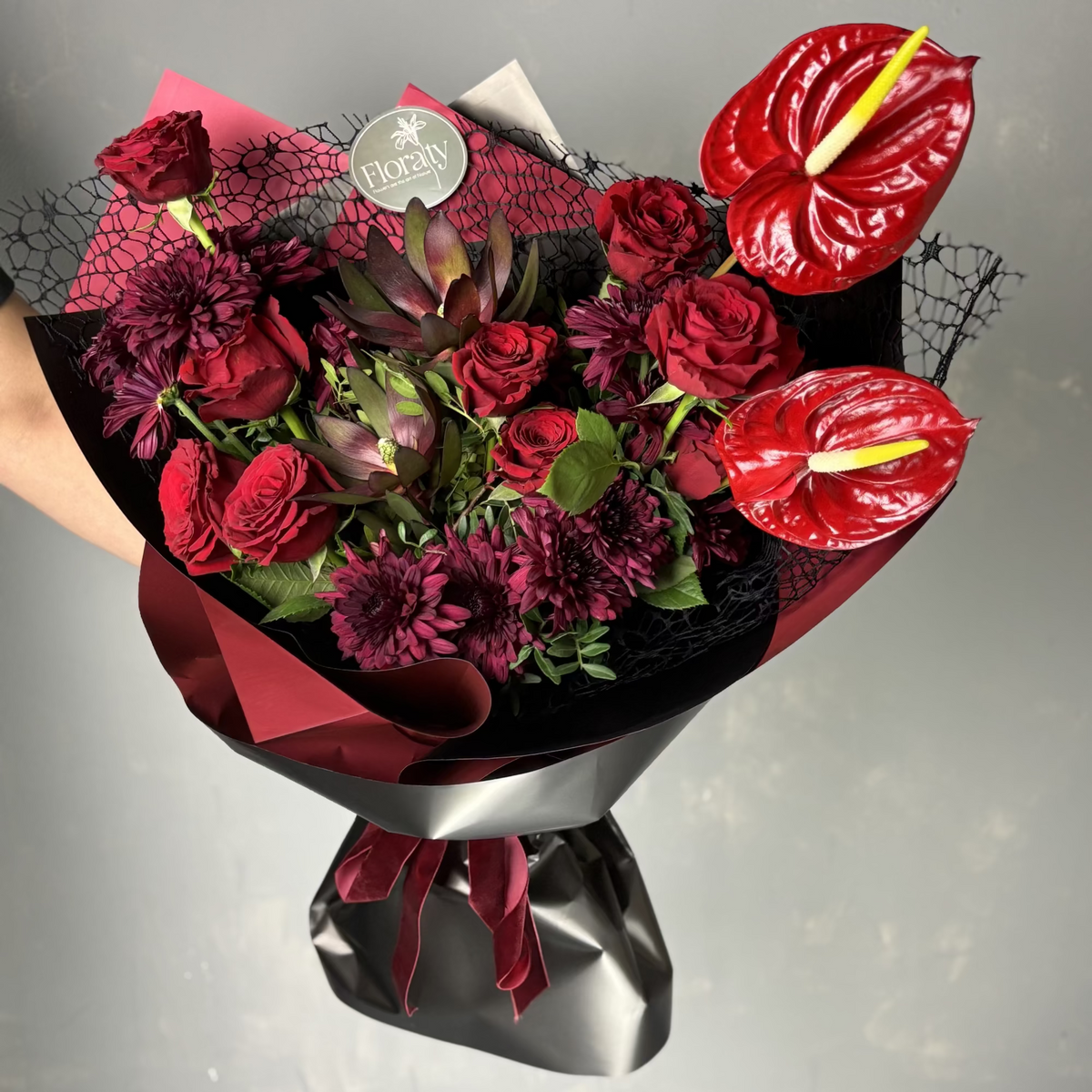 Bouquet of red flowers with a black wrap on a gray background