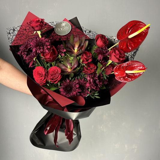 Bouquet of red flowers with anthuriums on a gray background