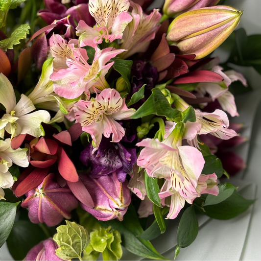 Bouquet of pink, purple, and green flowers on a white surface

