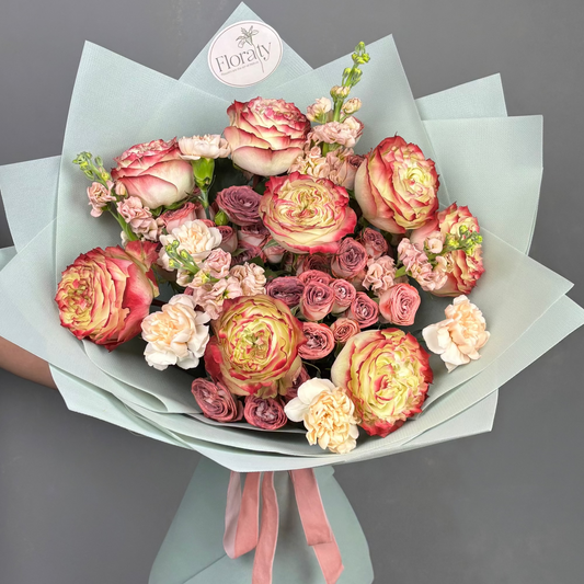 Bouquet of blush and cream flowers with a pink ribbon, branded 'Floraty' on grey background

