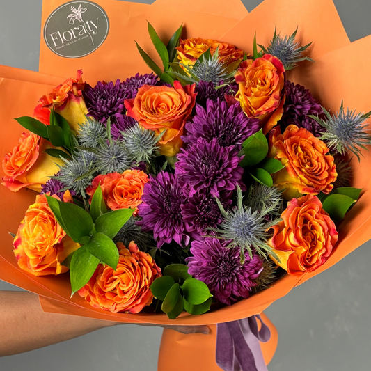 Bouquet of orange and purple flowers with a visible 'Floraly' logo on orange paper.

