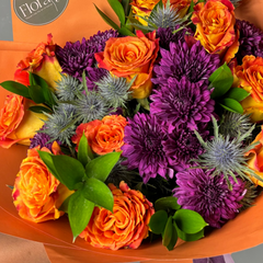 Bouquet of orange and purple flowers with an orange wrap, featuring the 'Floraty' brand.