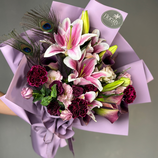 Floral bouquet with pink lilies, purple flowers, and peacock feathers on a gray background.