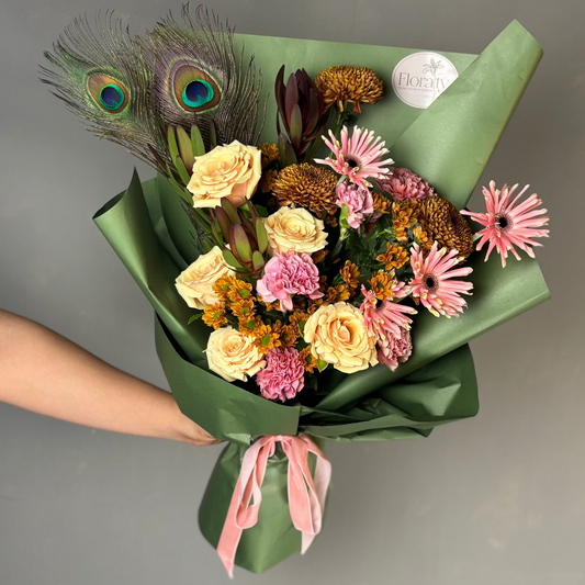 Bouquet of flowers with peacock feathers and a pink ribbon on a gray background


